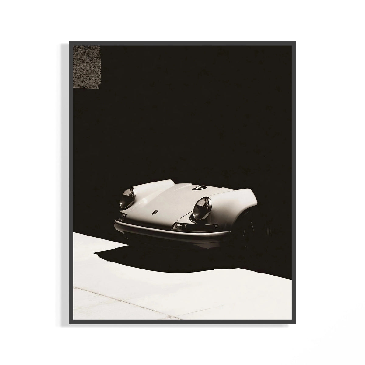 Vintage white Porsche 911 front view against dramatic black shadows, shown in a frame for display