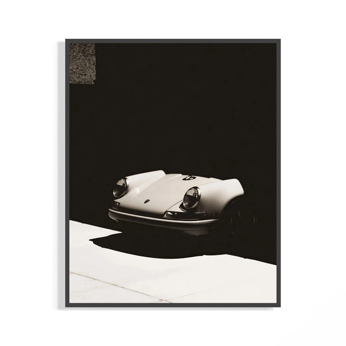 Vintage white Porsche 911 front view against dramatic black shadows, shown in a frame for display
