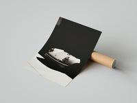 Monochrome Porsche 911 print of a white sports car on black, displayed beside a shipping cardboard tube