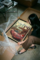 Woman carefully unboxing a Porsche 911 Retro Gas Station wall art poster from protective brown cardboard tube