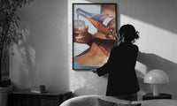 Pouring a Sparkling Drink print in a slim black frame being hung on a sunlit wall in a monochrome room