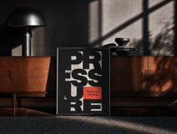 Black-framed Pressure Is a Privilege print on the floor in front of a dark wooden console