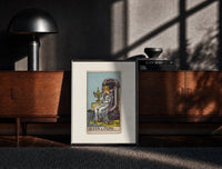 Black-framed Queen seated on throne holding cup print on a moody console with designer coffee-table books