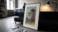 Queen seated on throne holding cup print in a slim black frame leaning on a dark sofa in a concrete print studio
