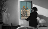 Queen of Swords print in a slim black frame being hung on a sunlit wall in a monochrome room