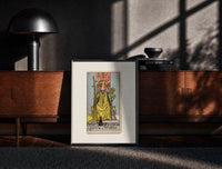 Black-framed Queen of Wands tarot card print on a moody console with designer coffee-table books