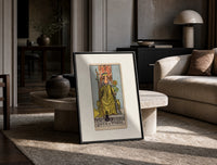 Queen of Wands tarot card print in a black frame leaning on a travertine table in a sunlit lounge