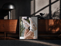 Black-framed Raised Legs in Beige Sneakers print on the floor in front of a dark wooden console