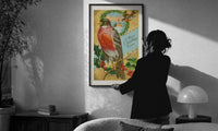 Bird A Merry Christmas to You print in a slim black frame being hung on a sunlit wall in a monochrome room