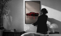 Red Ferrari LaFerrari print in a slim black frame being hung on a sunlit wall in a monochrome room