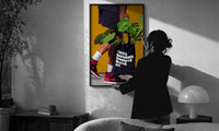 Plant Tote and Red High-Tops print in a slim black frame being hung on a sunlit wall in a monochrome room