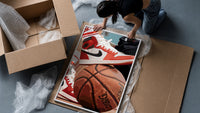 Red Sneakers on a Basketball framed print being unpacked from protective bubble wrap and a box
