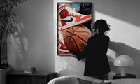 Red Sneakers on a Basketball print in a slim black frame being hung on a sunlit wall in a monochrome room