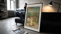 Woman serving glass of water print in a slim black frame leaning on a dark sofa in a concrete print studio