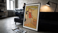 Woman in red bathing suit at beach print in a slim black frame leaning on a dark sofa in a concrete print studio