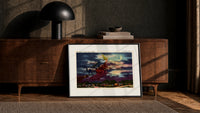 Witch flying on broomstick with cat print in a black frame leaning against a walnut console in lamplight