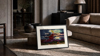 Witch flying on broomstick with cat print in a slim black frame leaning on a travertine coffee table