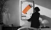 Salmon Lighter Seafood Market print in a slim black frame being hung on a sunlit wall in a monochrome room
