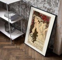 Woman with flowing hair holding feather poster in a black frame leaning beside a shelf in a raw-plaster loft