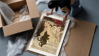 Woman with flowing hair holding feather framed print being unpacked from protective bubble wrap and a box