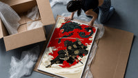 Oni-masked samurai leaping with drawn katana framed print being unpacked from protective bubble wrap and a box