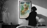 Santa A Merry Christmas print in a slim black frame being hung on a sunlit wall in a monochrome room