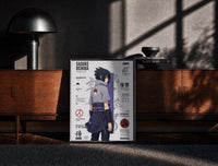 Black-framed Sasuke Uchiha standing with sword print on a moody console with designer coffee-table books