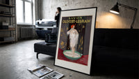 Woman bathing in soap suds print in a slim black frame leaning on a dark sofa in a concrete print studio
