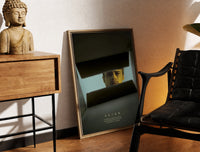 Brass-framed Se7en box scene print leaning in a warm styled corner by a sculpture