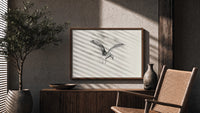 Seagull in flight print in a wood frame above a fluted sideboard beside an olive tree