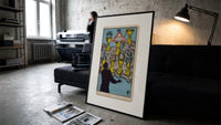 Seven Cups of Wands tarot card print in a slim black frame leaning on a dark sofa in a concrete print studio