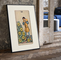 Man leaning on staff with pentacles print in a black frame leaning beside a vintage door on parquet