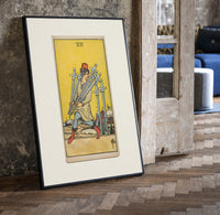 Man carrying five swords print in a black frame leaning beside a vintage door on parquet