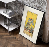 Man carrying five swords poster in a black frame leaning beside a shelf in a raw-plaster loft