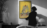 Seven of Swords print in a slim black frame being hung on a sunlit wall in a monochrome room