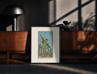 Black-framed Man holding staff among wands print on a moody console with designer coffee-table books