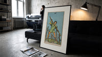 Man holding staff among wands print in a slim black frame leaning on a dark sofa in a concrete print studio