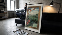 Landscape view of Paris from hills print in a slim black frame leaning on a dark sofa in a concrete print studio