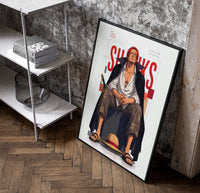 Red-haired man sitting on block poster in a black frame leaning beside a shelf in a raw-plaster loft