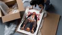 Red-haired man sitting on block framed print being unpacked from protective bubble wrap and a box