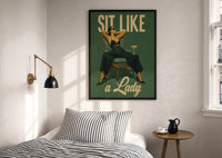 Sit Like a Lady print in a black frame above a bed with striped linens, a brass wall lamp and a sunlit window