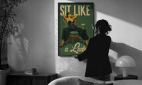 Sit Like a Lady print in a slim black frame being hung on a sunlit wall in a monochrome room