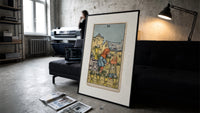 Two children exchanging cups of flowers print in a slim black frame leaning on a dark sofa in a concrete print studio