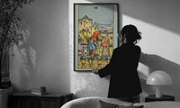 Six of Cups print in a slim black frame being hung on a sunlit wall in a monochrome room