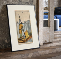 Ferryman poling boat with swords print in a black frame leaning beside a vintage door on parquet
