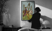 Six of Wands print in a slim black frame being hung on a sunlit wall in a monochrome room