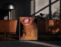 Black-framed Smile with a Butterfly Pendant print on the floor in front of a dark wooden console