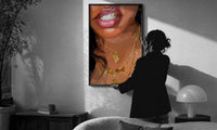 Smile with a Butterfly Pendant print in a slim black frame being hung on a sunlit wall in a monochrome room