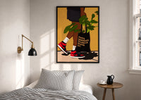 Sneakers and a Plant-Filled Tote print in a black frame above a bed with striped linens