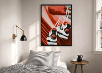 Sneakers Hanging from a Car Mirror print in a black frame above a bed with striped linens